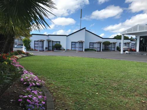 a large white building with a green lawn at Cascades Motor Lodge in Auckland