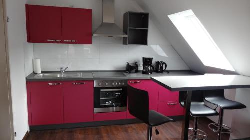 a small kitchen with red cabinets and a sink at Huus Veertein in Neuharlingersiel