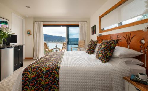 a bedroom with a large bed with a large window at Paku Palms in Tairua