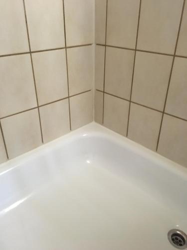 y baño con bañera blanca y azulejos blancos. en Gästehaus Hannelore, en Geiselwind