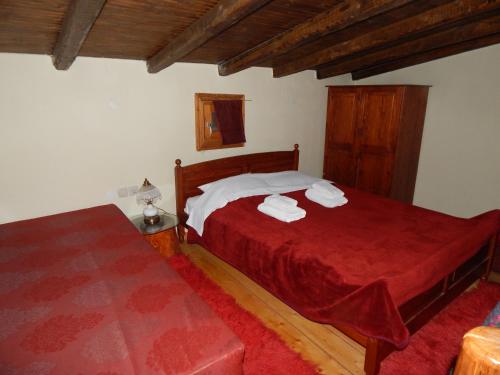 a bedroom with two beds with red sheets and white towels at Iaspis Guesthouse in Kastoria