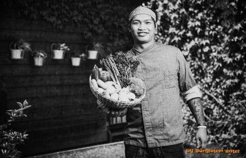 a man holding a basket of fruits and vegetables at Hotel Bürglstein in St. Wolfgang