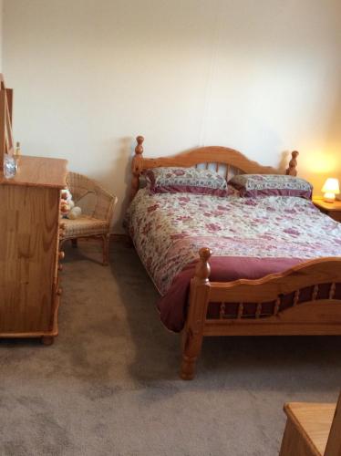 a bedroom with a wooden bed and a chair at Erne View Cottage in Kesh