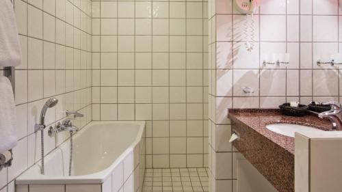 a bathroom with a sink, toilet and bathtub at Hotel Knudsens Gaard in Odense