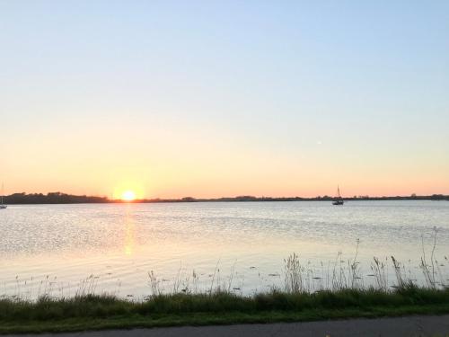 a sunset on a lake with a boat in the water at Schlei Idyll in Maasholm-Bad