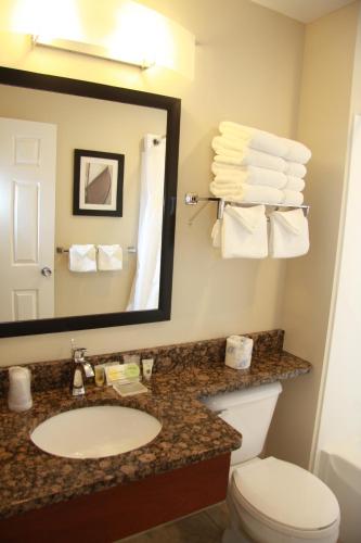 y baño con lavabo, espejo y aseo. en Budget Host Inn & Suites, en Saint Ignace