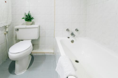 a white bathroom with a toilet and a bath tub at Sinkiat Thani Hotel in Satun