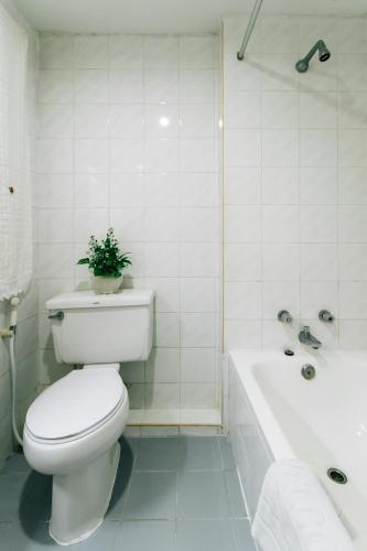 a white bathroom with a toilet and a bath tub at Sinkiat Thani Hotel in Satun