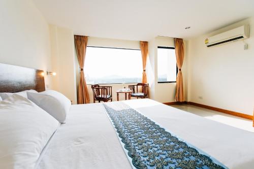 a bedroom with a large bed with a large window at Sinkiat Thani Hotel in Satun