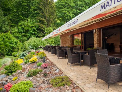 a patio with tables and chairs in front of a restaurant at Hotel Singer in Ludvíkov