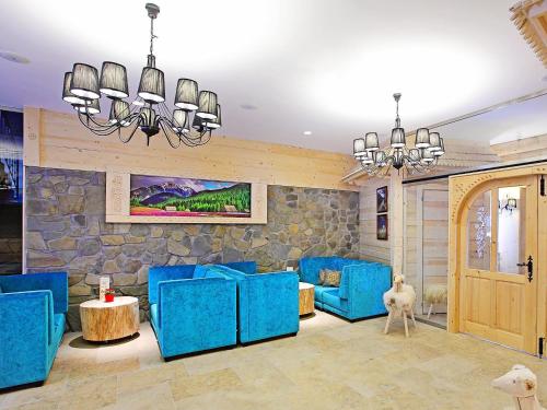 a living room with blue chairs and a stone wall at Hotel Gazdówka Spa in Osielsko