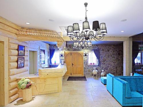 a living room with a chandelier and blue furniture at Hotel Gazdówka Spa in Osielsko