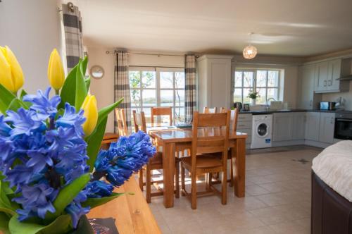 uma cozinha e sala de jantar com uma mesa e flores azuis em Erne View Cottages em Lisnaskea