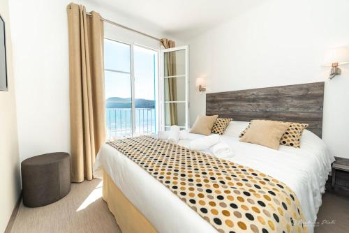 a bedroom with a large bed with a large window at Hôtel George Sand in La Seyne-sur-Mer