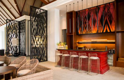 a restaurant with a bar with chairs and tables at Pullman Luang Prabang in Luang Prabang