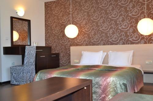 a hotel room with a bed and a desk and a mirror at Hotel Diamanti in Sozopol