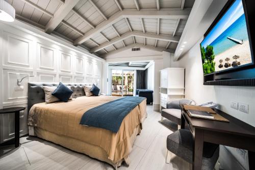 a bedroom with a bed and a desk and a television at Forte Village Resort - Villa Del Parco & Spa in Santa Margherita di Pula