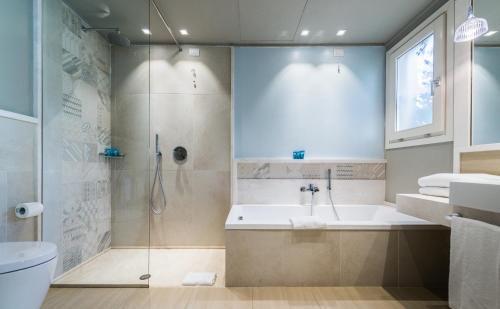 y baño con ducha, bañera y lavamanos. en Forte Village Resort - Le Palme, en Santa Margherita di Pula