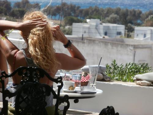 a woman sitting in a chair with a table with a drink at Galini Bungalows in Kionia