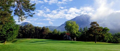 a golf course with a house and mountains in the background at The Golf Club Guest House in Menaggio
