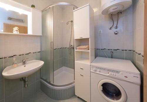 a bathroom with a washing machine and a sink at Breki Apartman in Podstrana