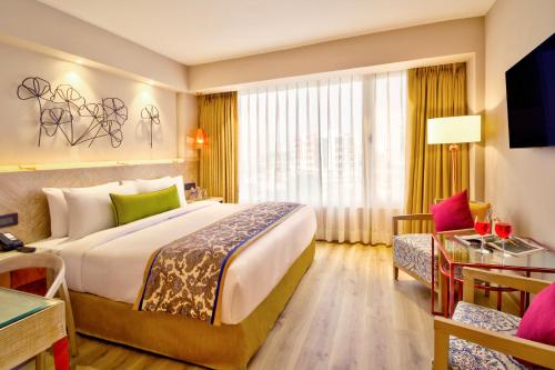 a hotel room with a large bed and a couch at Sarovar Premiere Jaipur in Jaipur