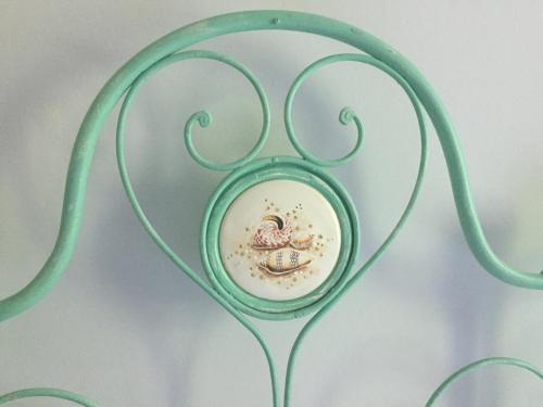 a green wrought iron bed with a plate on it at B&B Villa al Parco in Sala Baganza