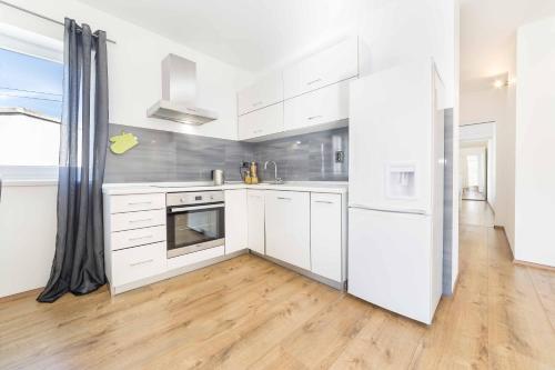 a kitchen with white appliances and a wooden floor at Apartments Tonka Centar in Vodice