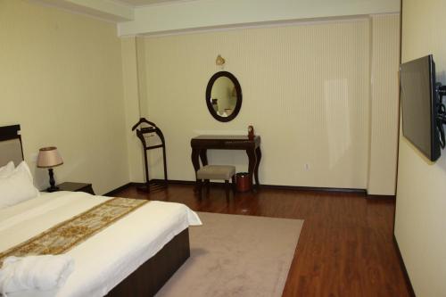 a bedroom with a bed and a desk and a mirror at Zargaron Plaza in Bukhara