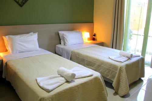 Dos camas en una habitación de hotel con toallas. en Your Home, en Kato Daratso