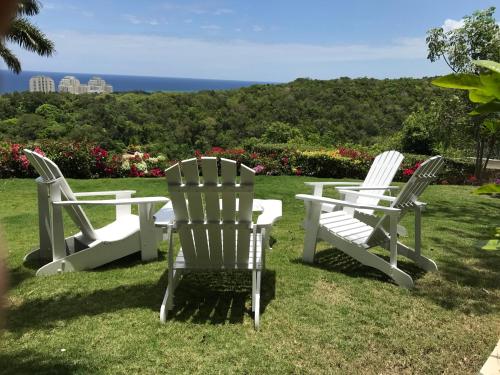 three white chairs and a table in the grass at Luxury Villa sleeps 6, Beach Access, Montego Bay in Montego Bay