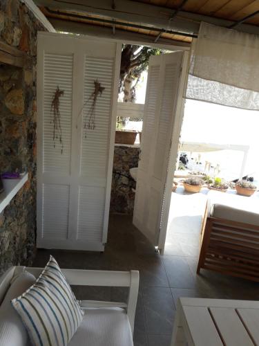 a porch with white doors and a couch and a table at Skajado Holiday Apartments in Stalida