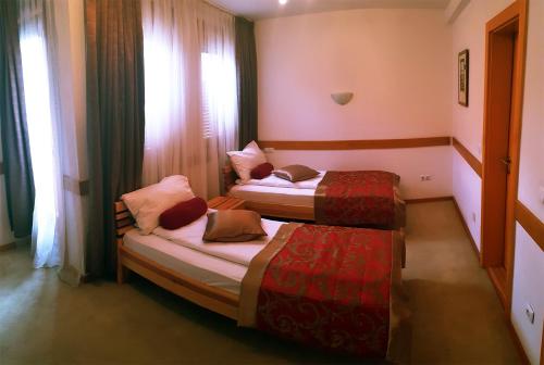 two beds in a small room with a window at Hotel Berr in Sarajevo