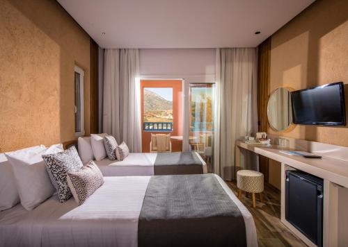 a hotel room with two beds and a television at Fodele Beach Water Park Resort in Fodele