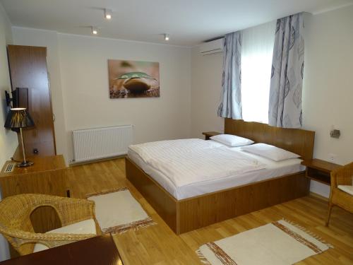 a bedroom with a bed and a chair and a window at Alabárdos Panzió és Apartmanház in Esztergom