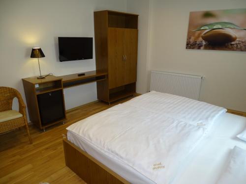 a bedroom with a bed and a tv and a chair at Alabárdos Panzió és Apartmanház in Esztergom