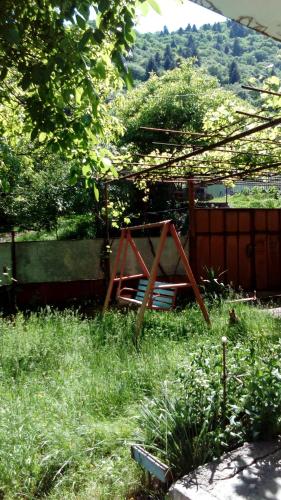 a garden with a wooden swing in the grass at Toma's vila in Borjomi