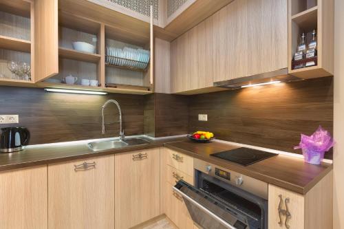 a kitchen with wooden cabinets and a sink at Argisht Partez Hotel ALL INCLUSIVE and beach with free sunbeds on the pool & beach bar Rebls in Golden Sands