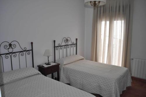 a bedroom with two beds and a window at Casa Rural La Fuente del Coso in Cabeza la Vaca