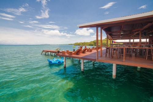 a dock with tables and a raft in the water at Aqui hoy cabañas in Bocas del Toro