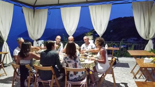 een groep mensen die aan een tafel zitten te eten bij B&B Villa Maristella in Lipari