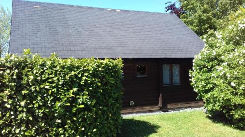 a house with a black roof and a hedge at Chalet Domaine du Hulobiet in Fromelennes
