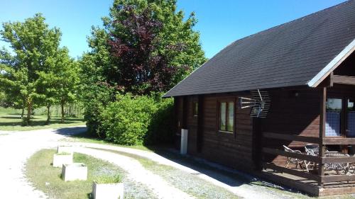 a small building with a porch next to a road at Chalet Domaine du Hulobiet in Fromelennes