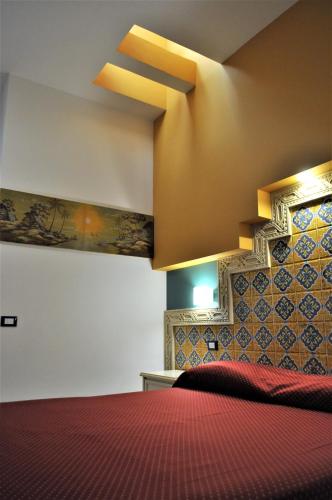 a bedroom with a bed with a red bedspread at Al-Tair in San Vito lo Capo
