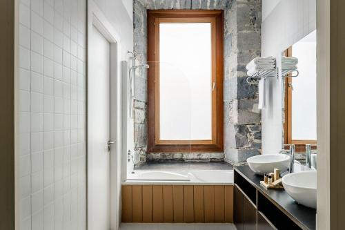 a bathroom with two sinks and a tub and a window at Hotel Balneario Orduña Plaza in Orduña