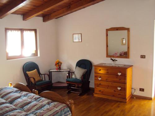 - une chambre avec deux chaises, une commode et un miroir dans l'établissement La casa di Beppe appartamento, à Danta