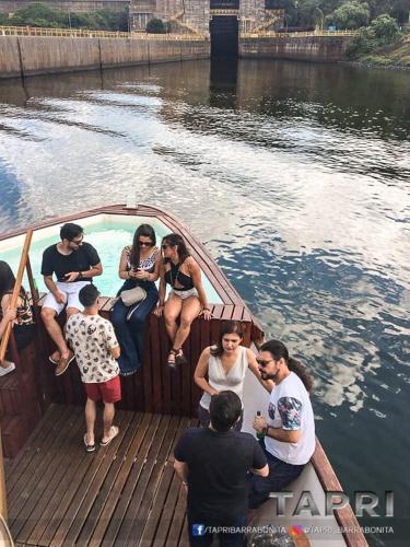 a group of people sitting in a boat on the water at Tapri - Hotel Flutuante in Barra Bonita