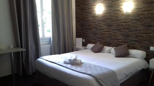 a bedroom with a white bed with a brick wall at Le Relax in Aurillac