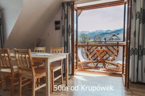 um quarto com uma mesa e cadeiras e uma varanda em Przy Szlaku Zakopane centrum pokoje & apartamenty em Zakopane