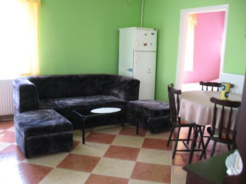 a living room with a black leather couch and a table at Apartman Alexa in Ábrahámhegy